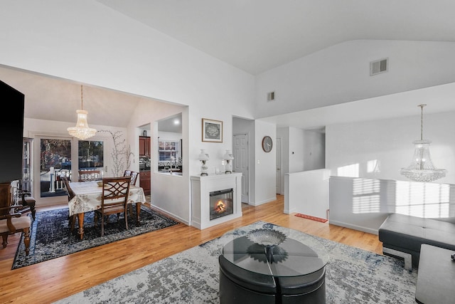 living room featuring a chandelier, high vaulted ceiling, and light hardwood / wood-style flooring