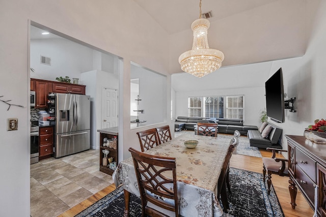 dining area with high vaulted ceiling and an inviting chandelier