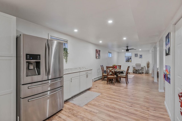 kitchen with stainless steel refrigerator with ice dispenser, ceiling fan, a baseboard heating unit, light hardwood / wood-style flooring, and white cabinetry