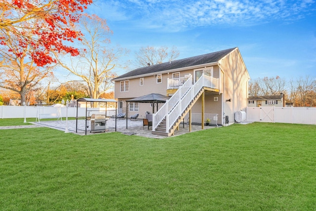 rear view of house featuring a gazebo, a lawn, and a patio