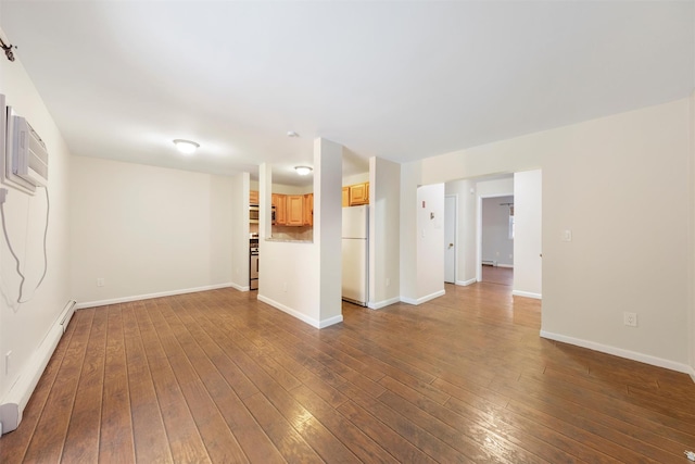 empty room with a baseboard heating unit, an AC wall unit, and dark wood-type flooring