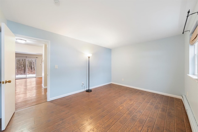 empty room featuring baseboard heating and hardwood / wood-style floors