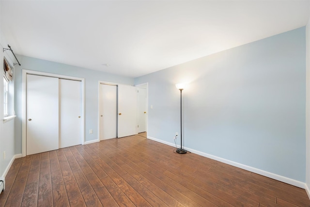 unfurnished bedroom with hardwood / wood-style flooring and multiple closets