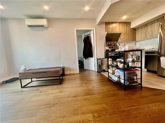 kitchen with dishwasher, tasteful backsplash, a wall mounted AC, and hardwood / wood-style flooring