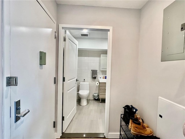 bathroom with tile patterned floors, toilet, and electric panel