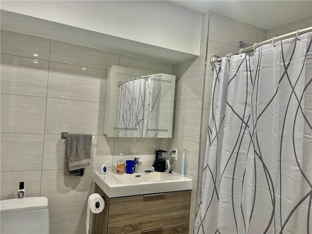 bathroom featuring tasteful backsplash, vanity, tile walls, and toilet