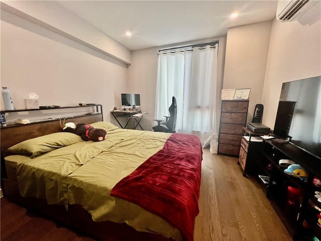 bedroom featuring hardwood / wood-style floors and a wall mounted AC