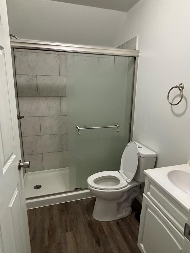 bathroom featuring walk in shower, vanity, wood-type flooring, and toilet