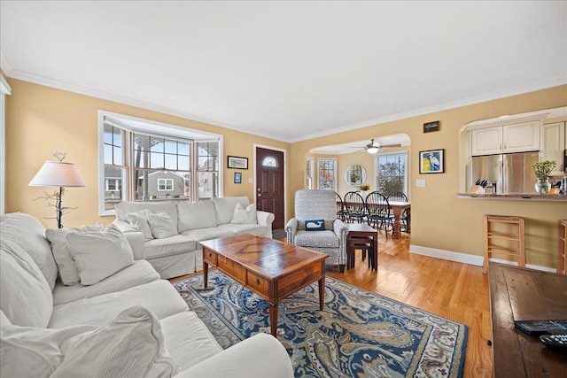 living room with light hardwood / wood-style flooring, a wealth of natural light, and ornamental molding