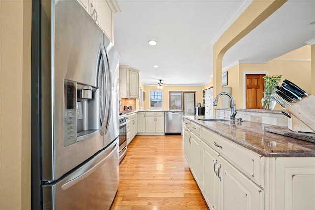 kitchen with sink, kitchen peninsula, light hardwood / wood-style floors, appliances with stainless steel finishes, and ornamental molding