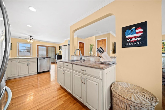 kitchen with appliances with stainless steel finishes, crown molding, sink, white cabinets, and light hardwood / wood-style floors