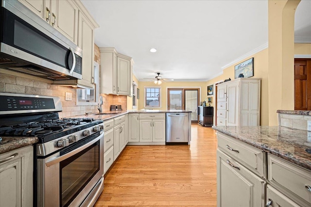 kitchen with stainless steel appliances, kitchen peninsula, crown molding, decorative backsplash, and light wood-type flooring