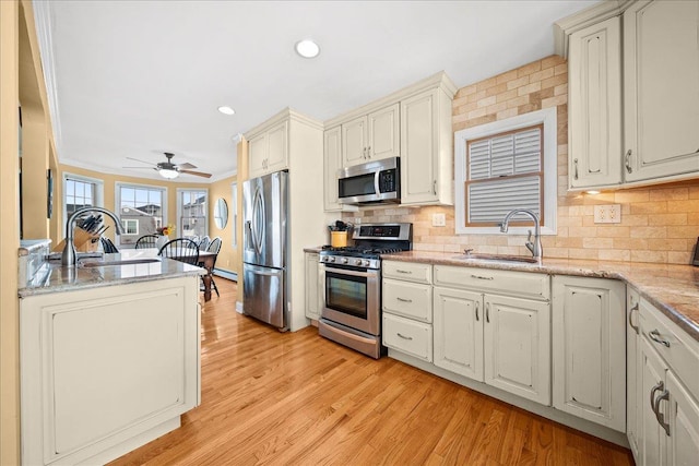 kitchen with stainless steel appliances, ceiling fan, crown molding, sink, and light hardwood / wood-style flooring