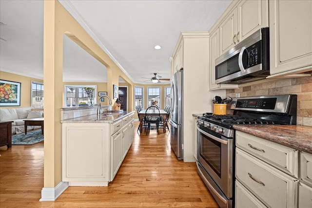 kitchen with crown molding, ceiling fan, light hardwood / wood-style floors, and appliances with stainless steel finishes