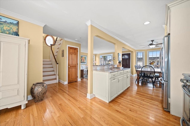 kitchen featuring white cabinetry, ceiling fan, stainless steel appliances, crown molding, and light hardwood / wood-style floors