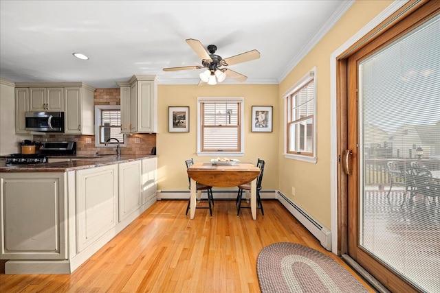 kitchen with a baseboard heating unit, crown molding, ceiling fan, light hardwood / wood-style floors, and stainless steel appliances