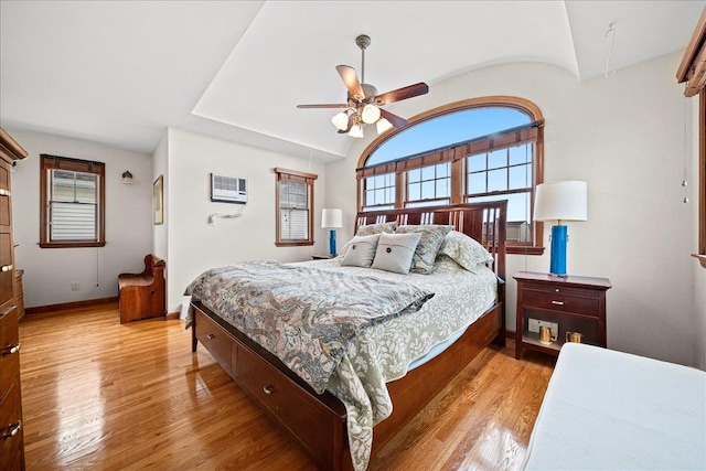 bedroom featuring a wall mounted air conditioner, ceiling fan, and light hardwood / wood-style flooring