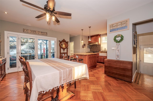 dining space featuring ceiling fan, sink, light parquet flooring, and french doors