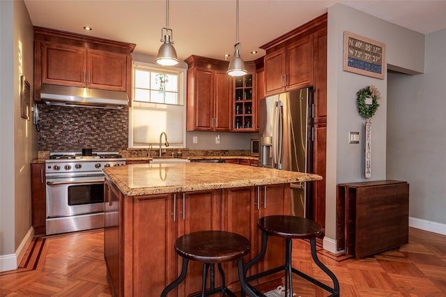 kitchen featuring light stone countertops, stainless steel appliances, decorative light fixtures, a center island, and light parquet flooring