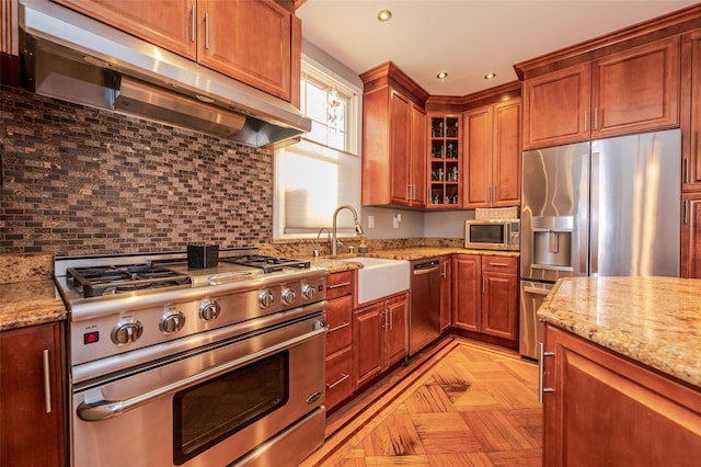 kitchen featuring light stone countertops, decorative backsplash, stainless steel appliances, sink, and light parquet flooring