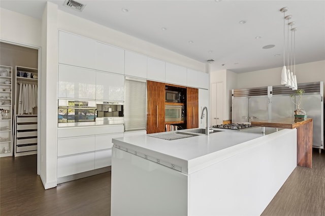 kitchen featuring white cabinets, an island with sink, pendant lighting, and dark hardwood / wood-style floors