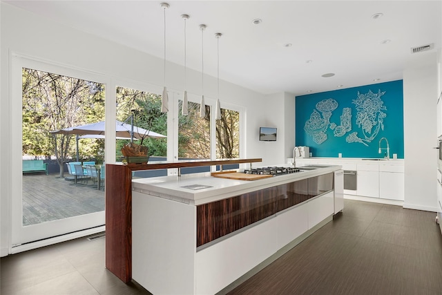 kitchen with white cabinets, pendant lighting, sink, and a kitchen island with sink