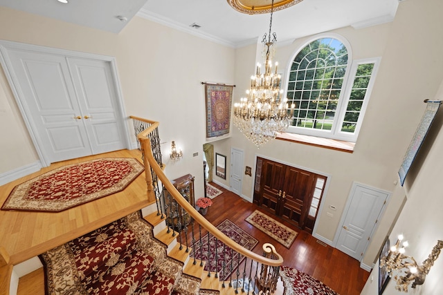 entryway featuring dark hardwood / wood-style flooring, ornamental molding, and a notable chandelier