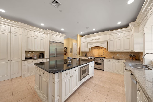 kitchen featuring light tile patterned floors, built in appliances, tasteful backsplash, and sink