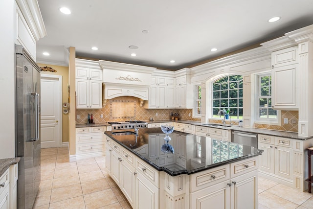 kitchen with sink, a kitchen island, light tile patterned floors, and appliances with stainless steel finishes