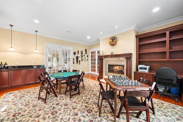 dining space with crown molding, french doors, a premium fireplace, and light hardwood / wood-style flooring