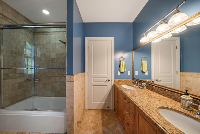 bathroom featuring vanity, combined bath / shower with glass door, and tile walls