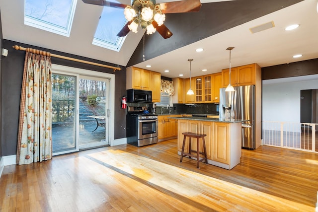 kitchen with a skylight, sink, a center island, light hardwood / wood-style flooring, and appliances with stainless steel finishes