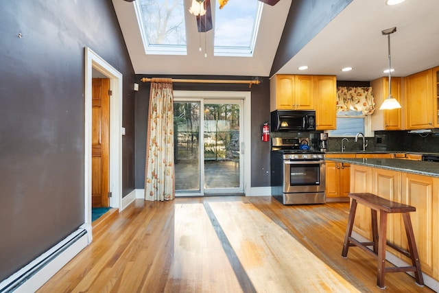 kitchen with stainless steel range oven, hanging light fixtures, a baseboard heating unit, and vaulted ceiling with skylight