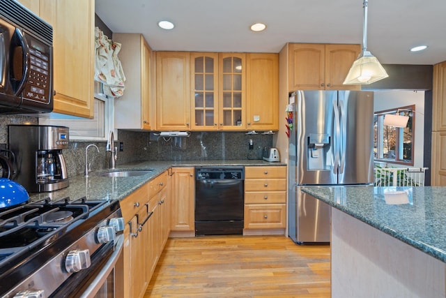 kitchen with sink, black appliances, pendant lighting, light hardwood / wood-style flooring, and dark stone countertops