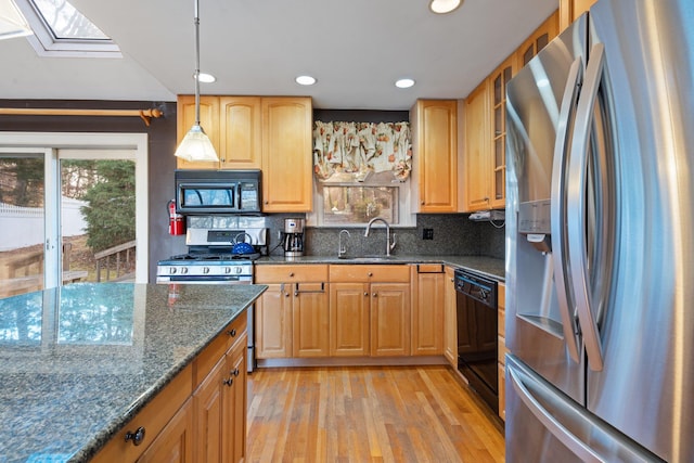 kitchen with black appliances, sink, a skylight, tasteful backsplash, and light hardwood / wood-style floors