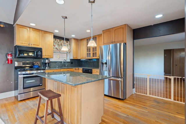 kitchen featuring a center island, black appliances, light hardwood / wood-style flooring, tasteful backsplash, and decorative light fixtures