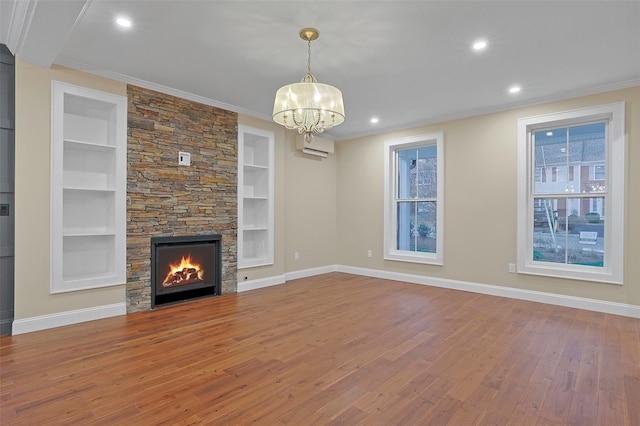 unfurnished living room with a stone fireplace, a chandelier, built in features, and wood-type flooring