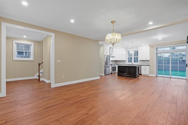 unfurnished living room with an inviting chandelier, ornamental molding, sink, and light hardwood / wood-style flooring