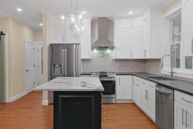 kitchen with a center island, stainless steel appliances, light hardwood / wood-style flooring, and wall chimney range hood