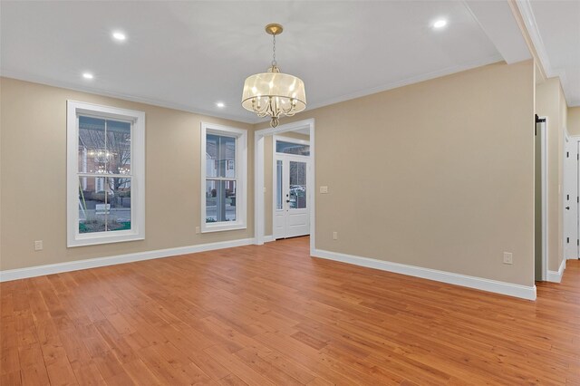 spare room with light hardwood / wood-style flooring, a notable chandelier, and crown molding