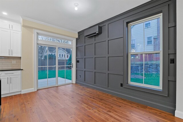 unfurnished room with a wall mounted air conditioner, light hardwood / wood-style floors, and ornamental molding