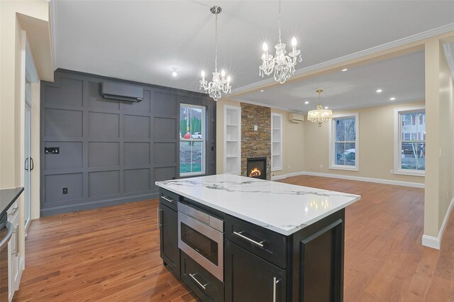 kitchen with a wall mounted air conditioner, appliances with stainless steel finishes, light hardwood / wood-style floors, and hanging light fixtures