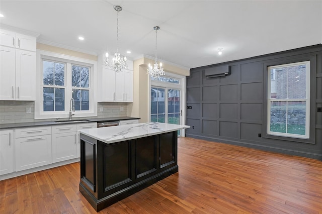 kitchen featuring decorative backsplash, a wall unit AC, white cabinetry, and sink