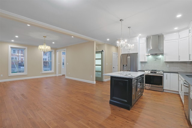 kitchen featuring a kitchen island, decorative light fixtures, wall chimney range hood, and appliances with stainless steel finishes