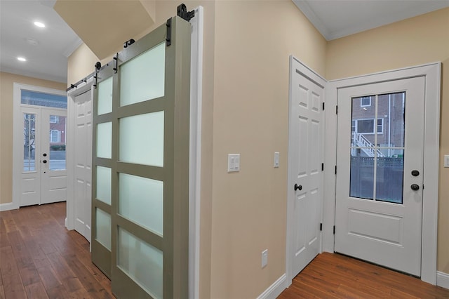 foyer featuring a barn door, crown molding, and dark wood-type flooring