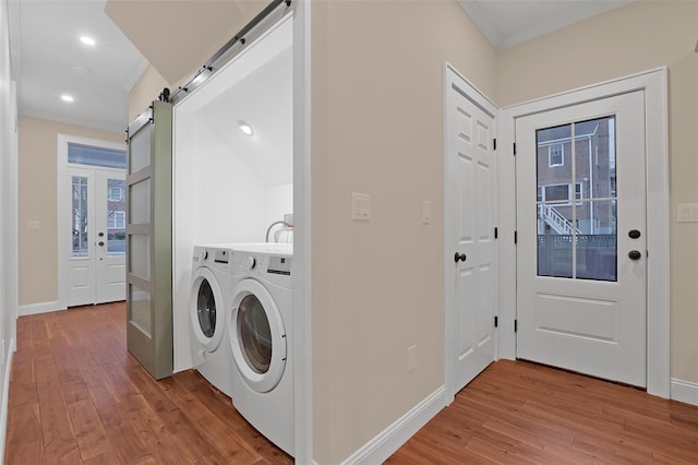 laundry area with french doors, crown molding, a barn door, independent washer and dryer, and wood-type flooring