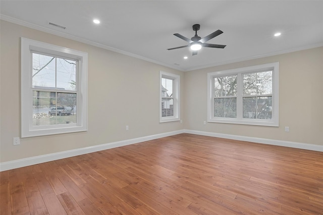 spare room featuring a wealth of natural light, crown molding, and light wood-type flooring