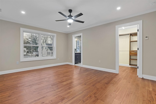 interior space with a spacious closet, ceiling fan, light hardwood / wood-style flooring, crown molding, and a closet