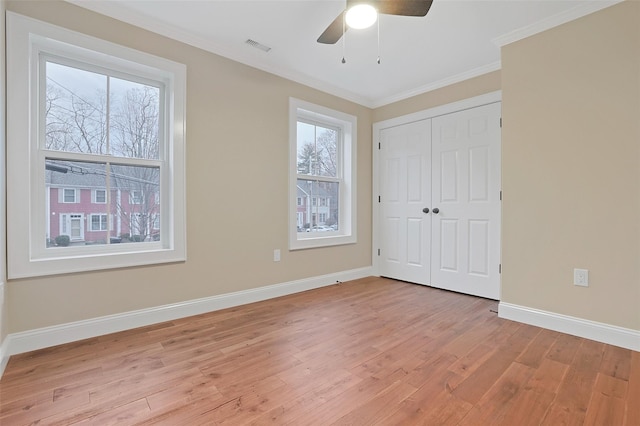 unfurnished bedroom with a closet, light hardwood / wood-style flooring, multiple windows, and ceiling fan