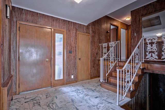 foyer entrance featuring ornamental molding and wooden walls